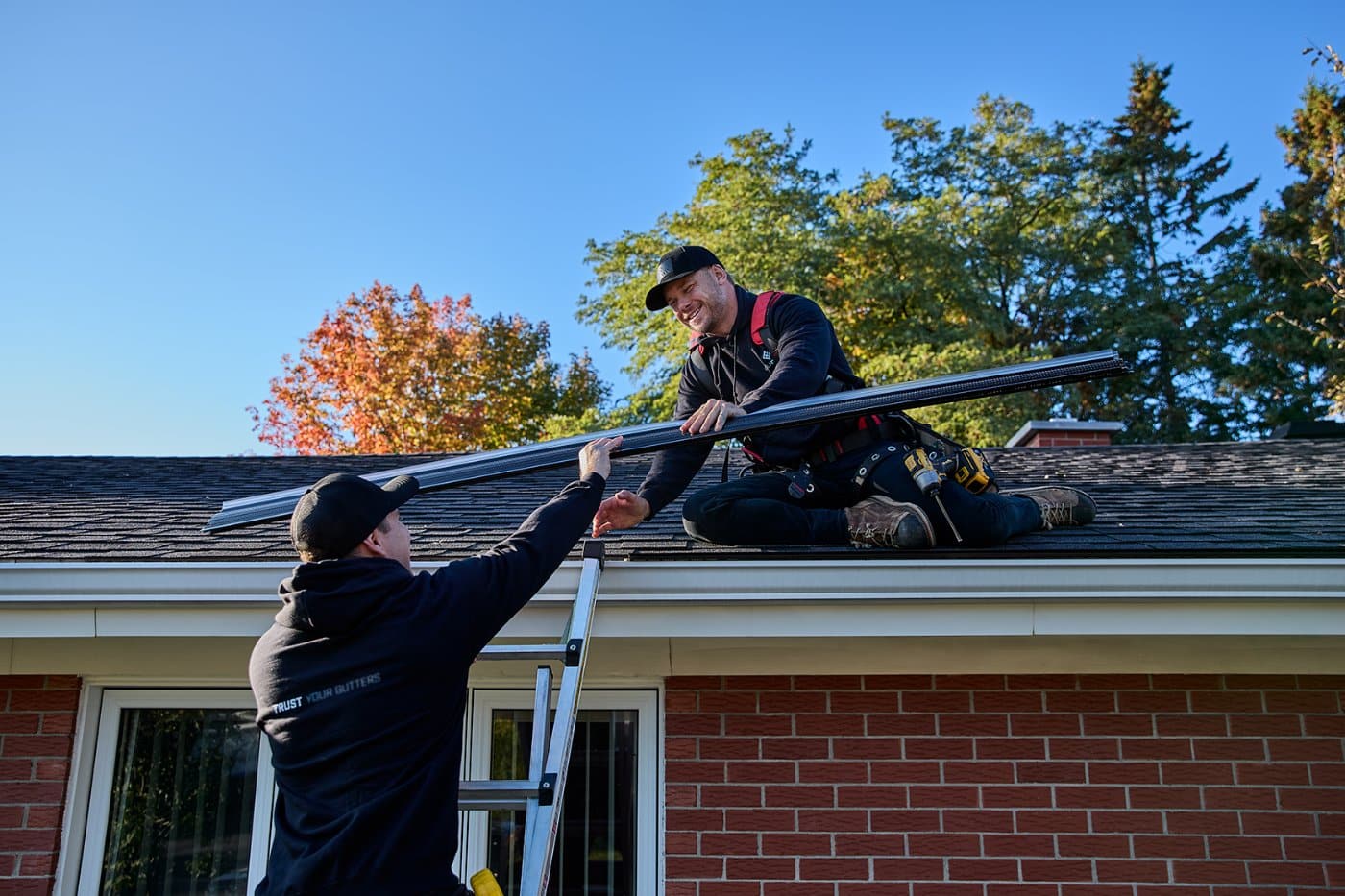 Installers fitting an Alu-Rex gutter guard on an existing gutter